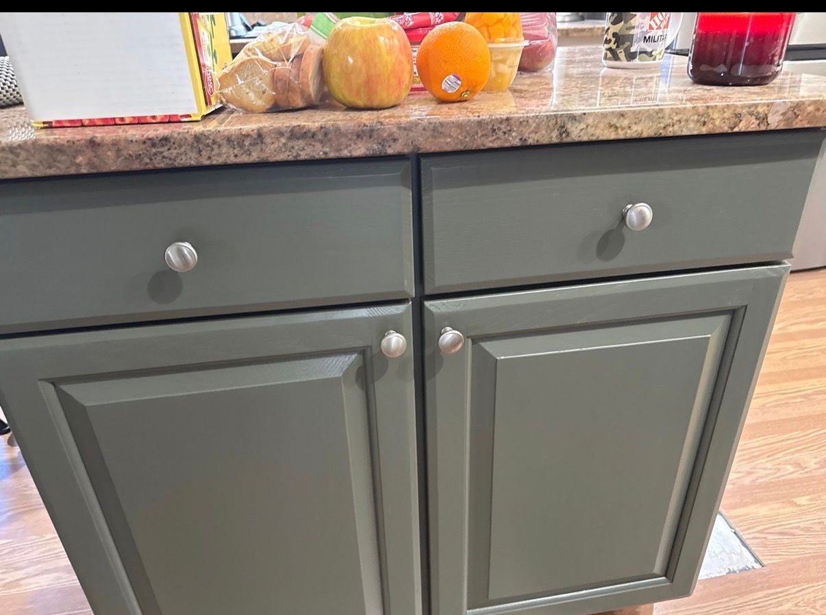 Gray kitchen cabinet with drawers and fruit on a granite countertop