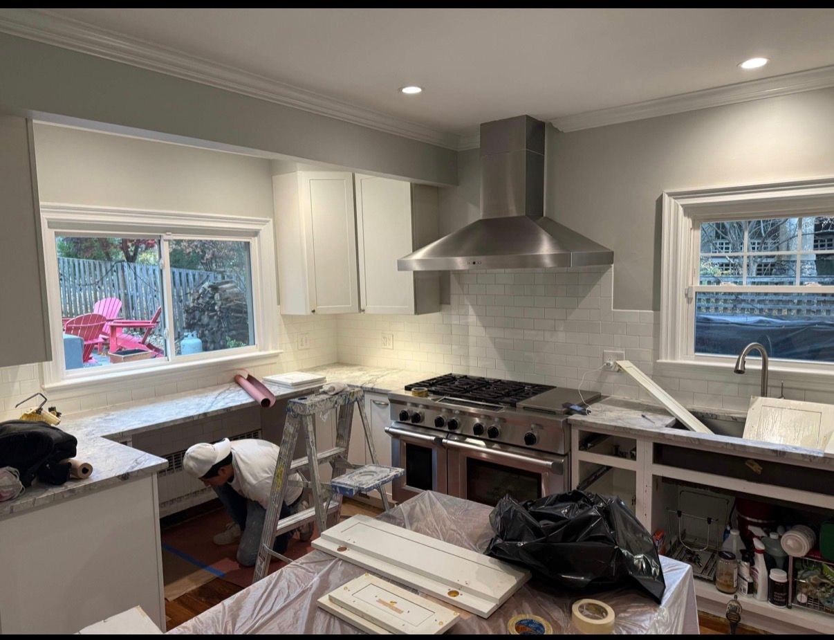 Renovating kitchen with white cabinets, stainless range hood, and boxes covering the island and counters