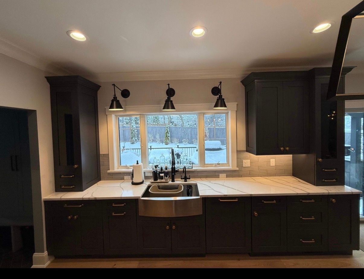 Modern kitchen with dark cabinets, farmhouse sink, and large window over the countertop