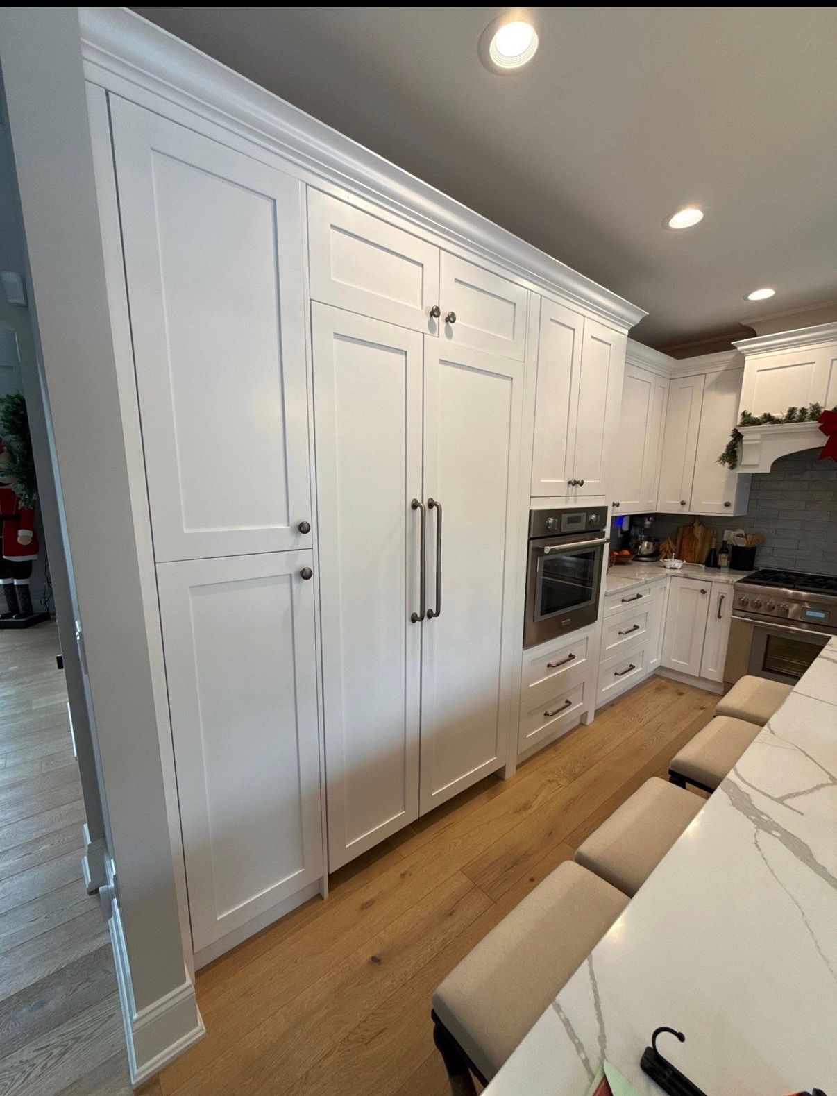 Bright white modern kitchen with built-in appliances, wood floor, and marble island counter