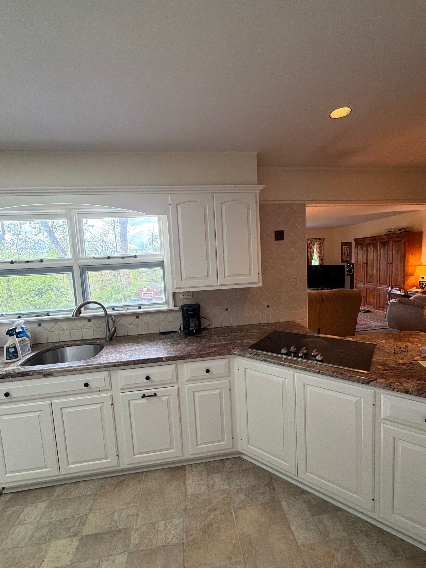 Spacious kitchen with wooden cabinets, granite counters, sink under window, and built-in oven