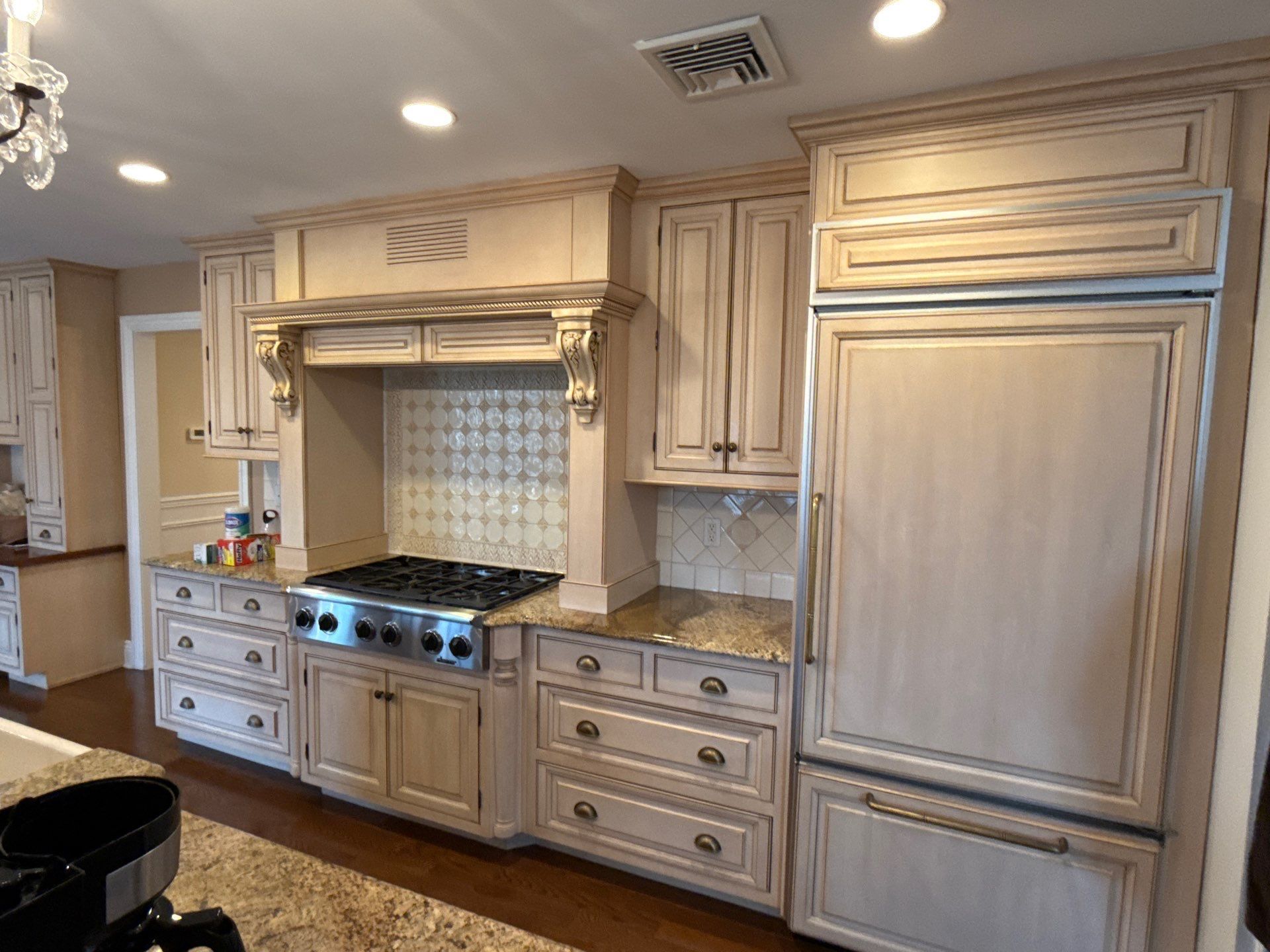 Bright kitchen with white cabinets, stainless stove, granite counters, and wood floors