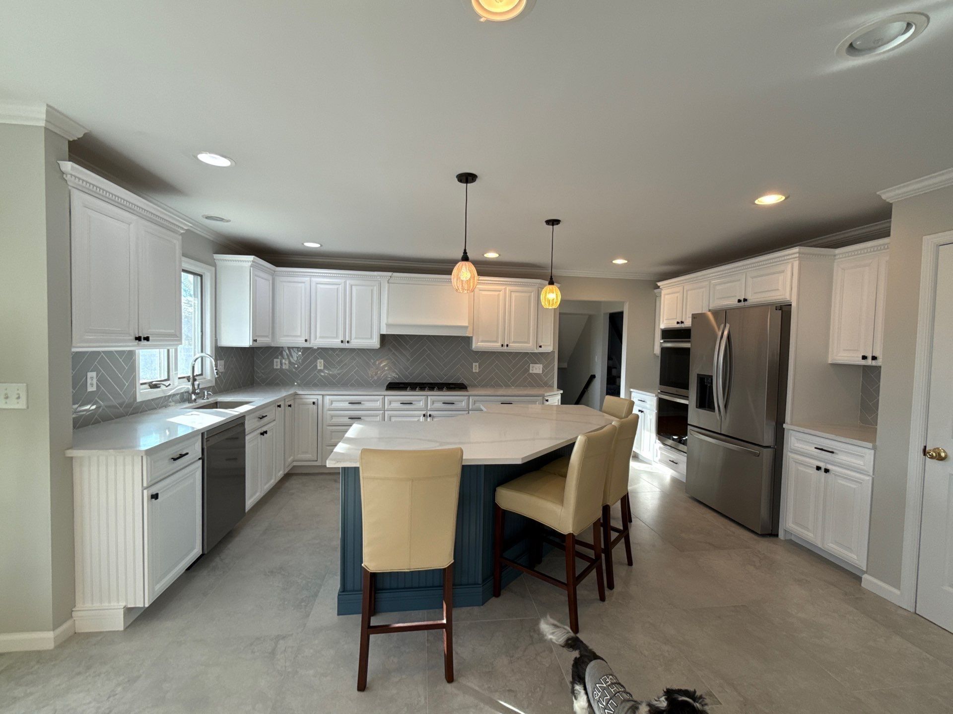 Bright modern kitchen with white cabinets, large island, stainless steel appliances, and two beige barstools