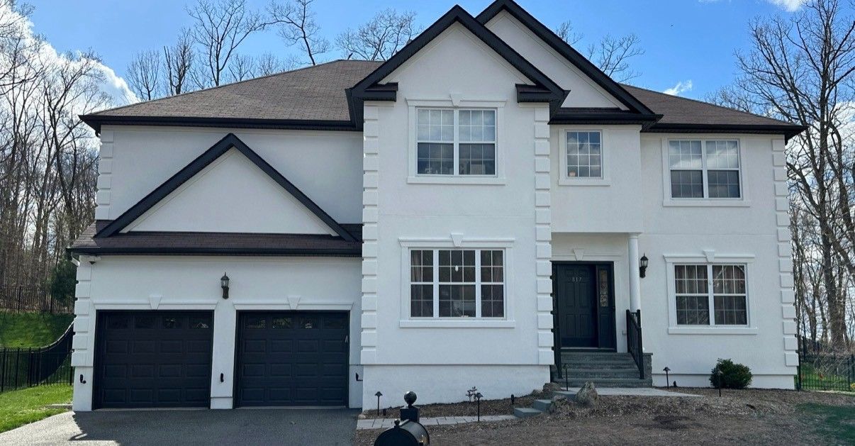 Blue split-level house with white trim, stone entry, and a two-car garage behind a paved driveway.