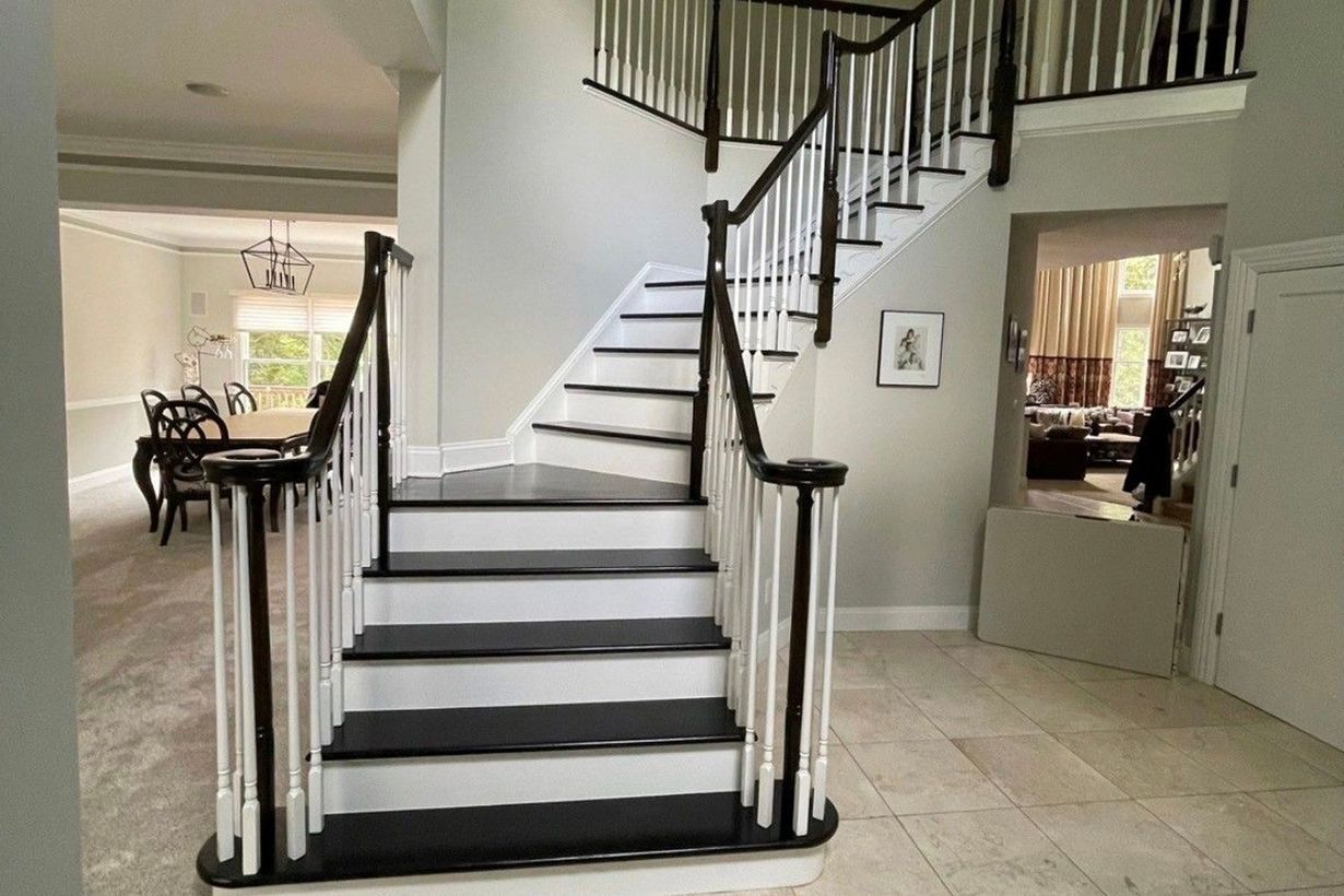 Interior foyer with a white staircase, black railings, and tiled floor leading to an upper landing
