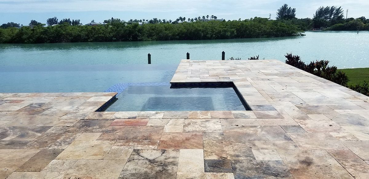 Swimming pool with a view of a body of water and lush green trees.
