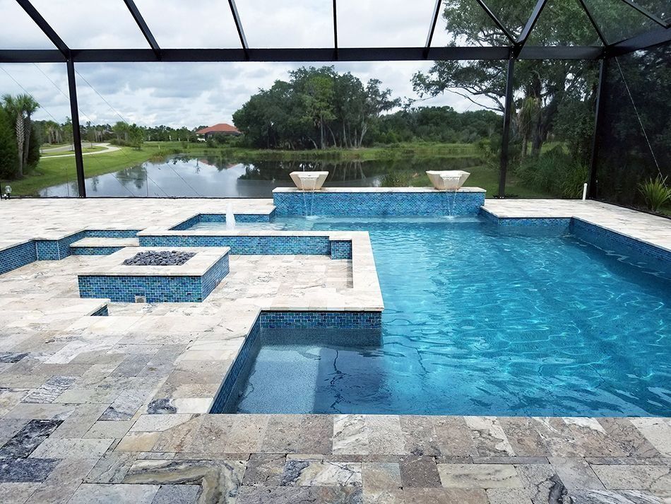 Swimming pool with blue tile and stone decking, screened enclosure, and scenic view of a lake.