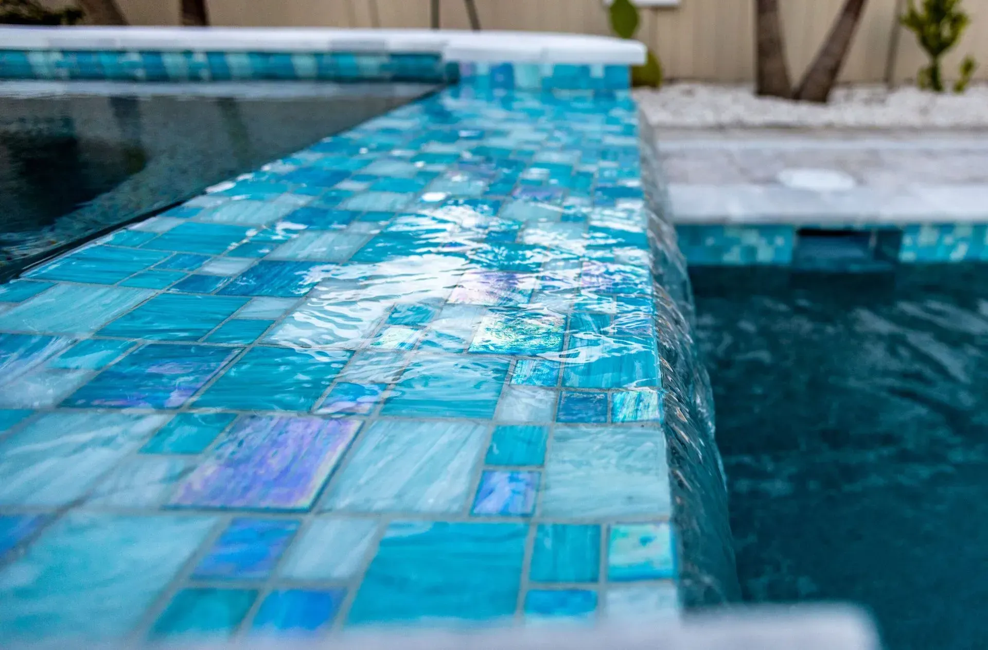 Water cascading over blue mosaic tiles into a pool.