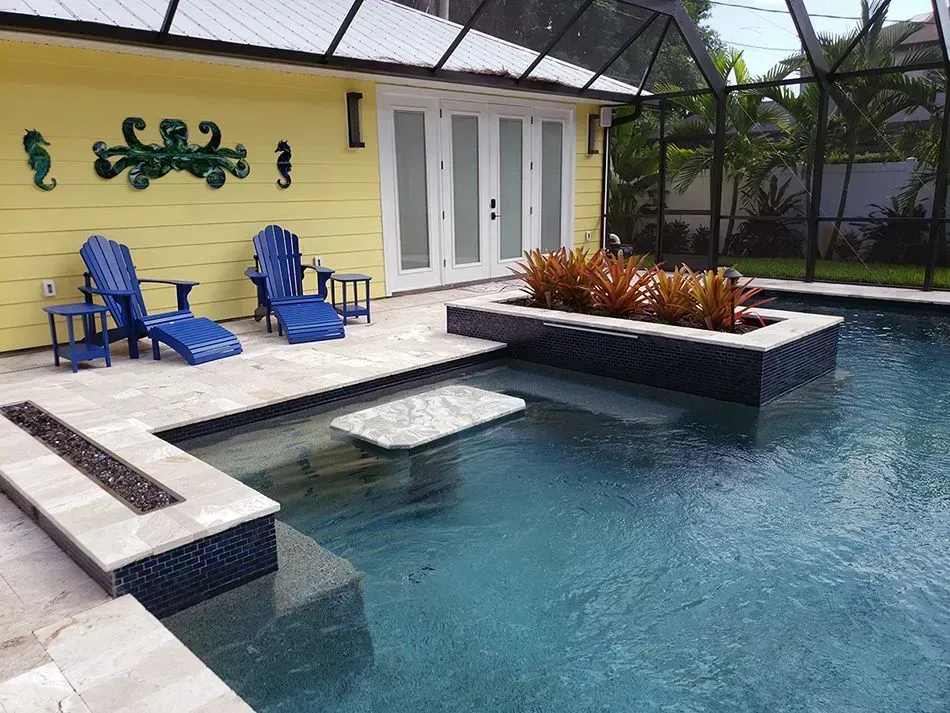 Poolside lounge area: blue chairs, fire pit, raised planter, and yellow house.