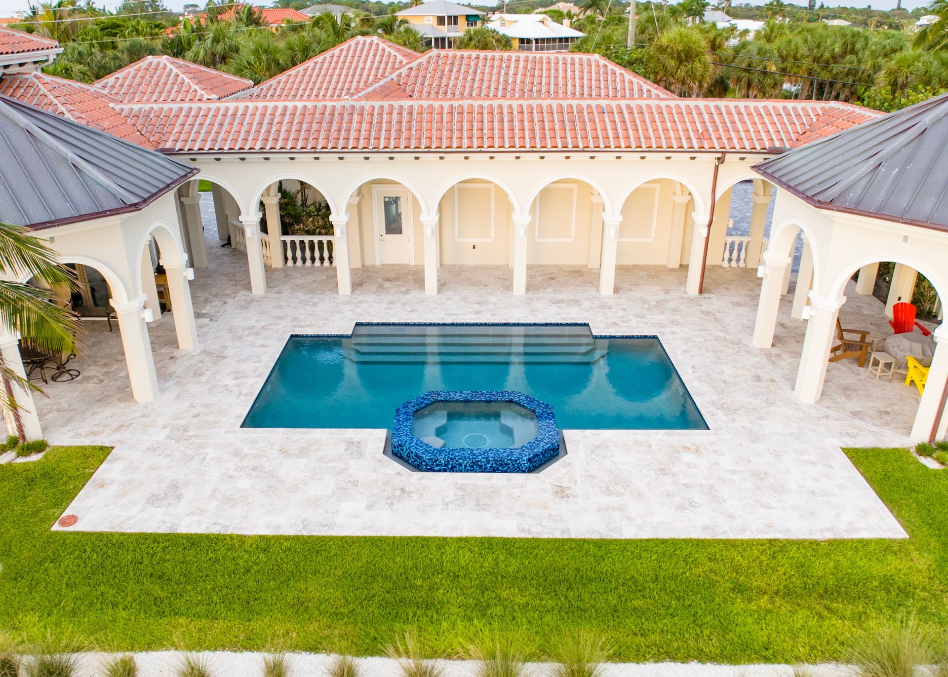 Luxury home courtyard with pool and spa, beige tile, red tile roof.