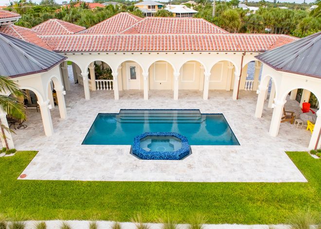 Luxury home courtyard with pool and spa, beige tile, red tile roof.