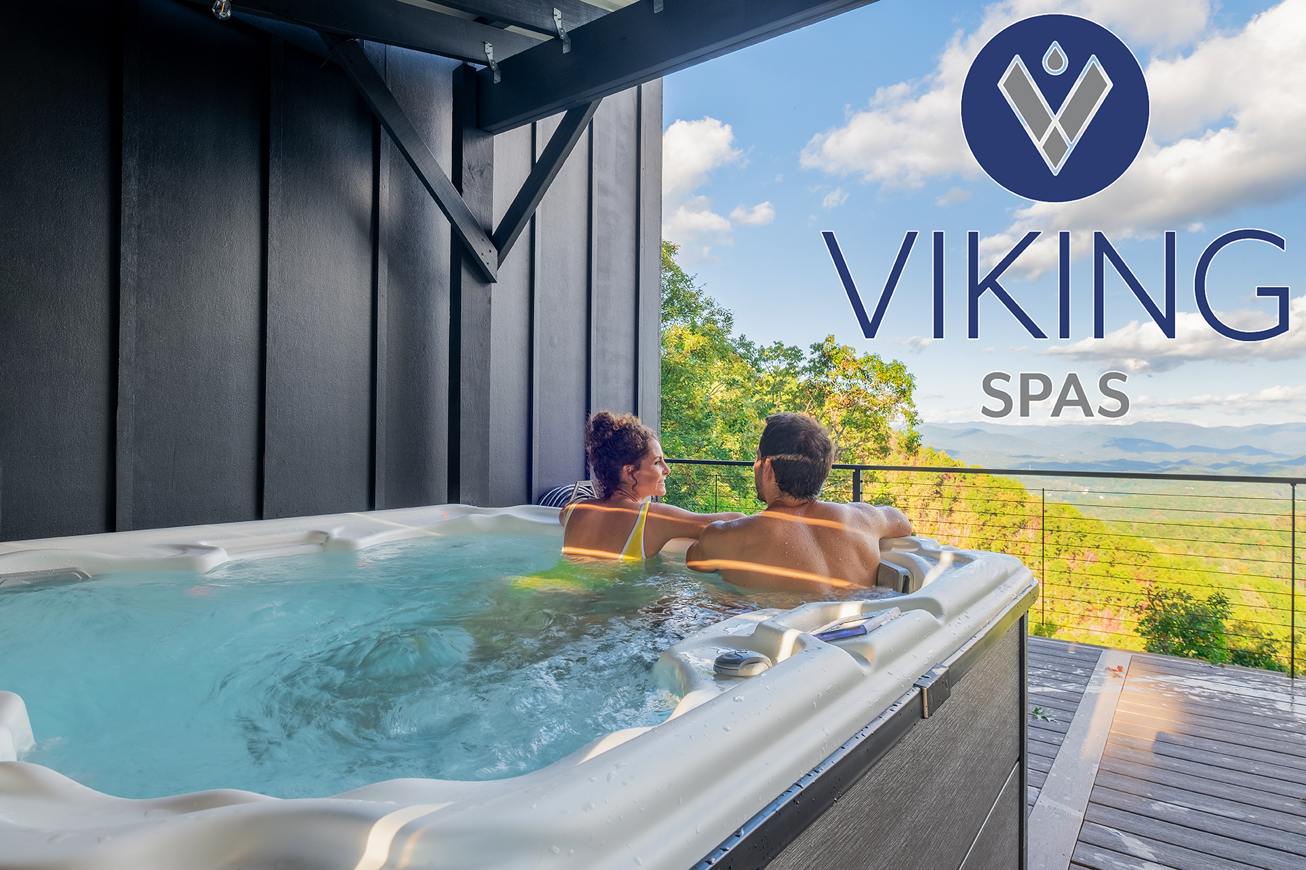 Couple relaxing in a hot tub outdoors, overlooking a scenic view. Viking Spas logo visible.