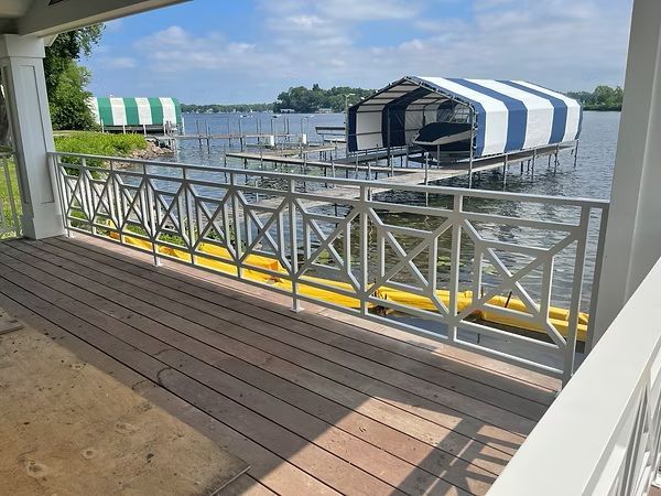 Waterside dock with striped canopy boats and white railings, viewed from a wooden deck
