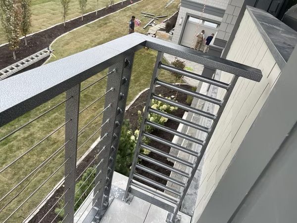 Narrow metal staircase and balcony on an outdoor building, viewed from above.