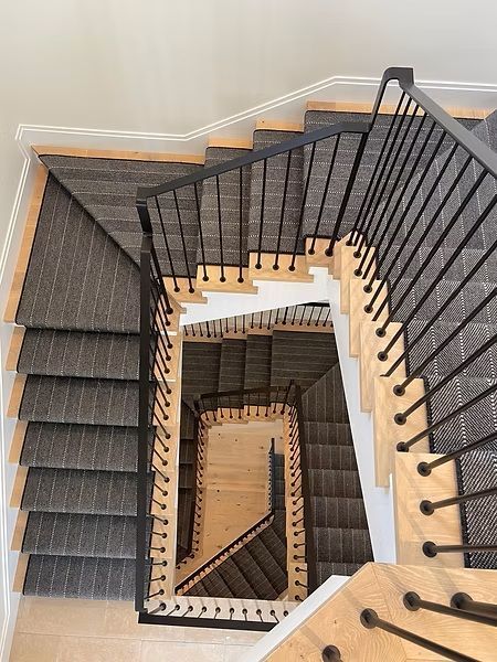 Top-down view of a modern spiral staircase with dark railings and light wood steps.