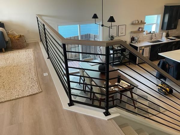 Modern home interior with staircase, black railing, and open loft overlooking a bright living area
