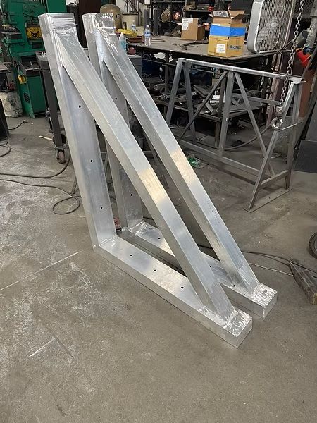 Silver metal frame structure in a workshop, resting on a concrete floor.