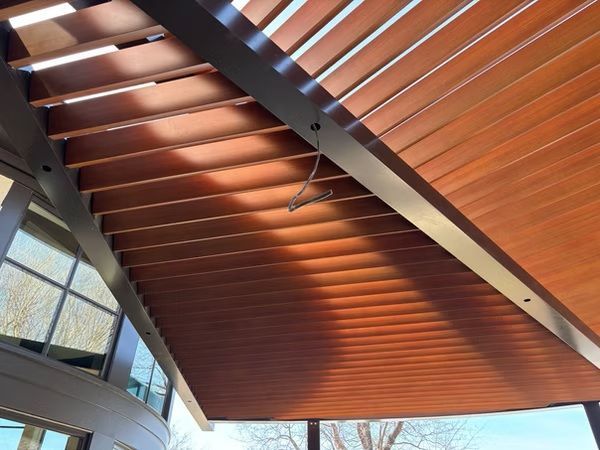 Wooden slatted ceiling with warm light and large windows in a modern interior