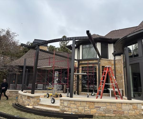 Stone patio renovation with scaffolding and ladders outside a modern building under construction