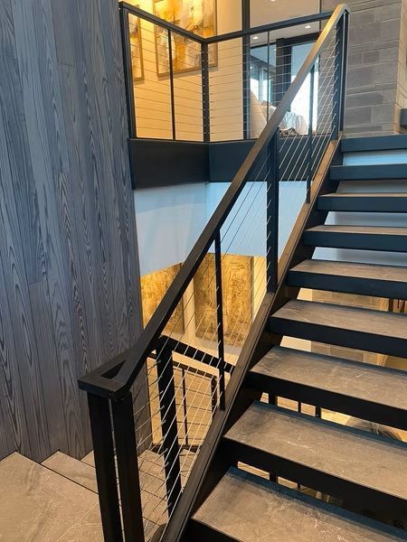 Modern staircase with black metal railing, wood steps, and warm-lit interior landing