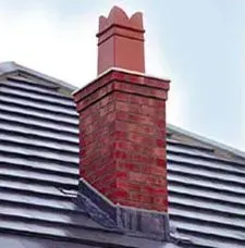 Brick chimney on a tiled roof with a decorative top, red color.