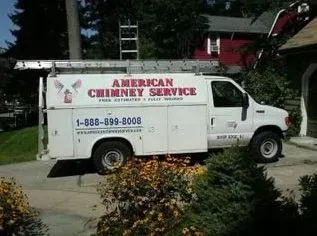 White van for American Chimney Service parked in front of a house, ladder on top.