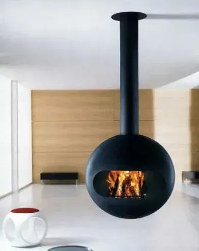 Black, spherical fireplace suspended from ceiling, with fire visible through an opening. Modern living room setting.