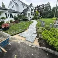 Pathway under construction leading to a white house with landscaping.