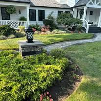 Stone pathway leading to a house with a green lawn and landscaping.