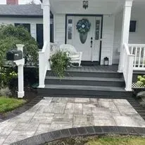 Front porch with a brick walkway and a black door. A mailbox stands near the steps.