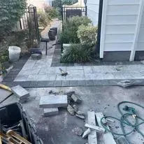 Construction site with partially completed paved walkway, building, and equipment.