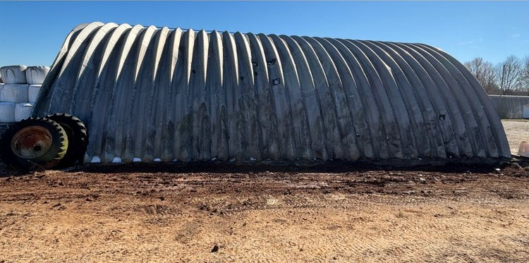 A large metal structure is sitting in the middle of a dirt field.