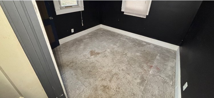 A room with a carpeted floor and black walls.