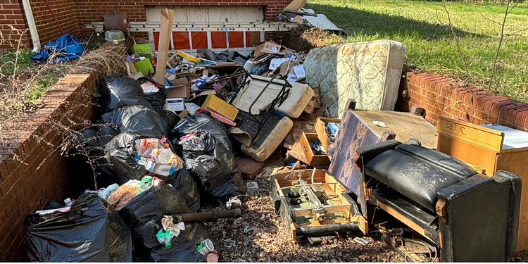 A pile of trash is sitting in front of a brick wall.
