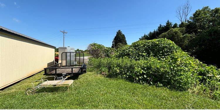 A trailer is parked in a grassy yard next to a building.