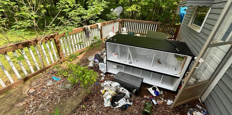 A house with a lot of trash on the ground in front of it.