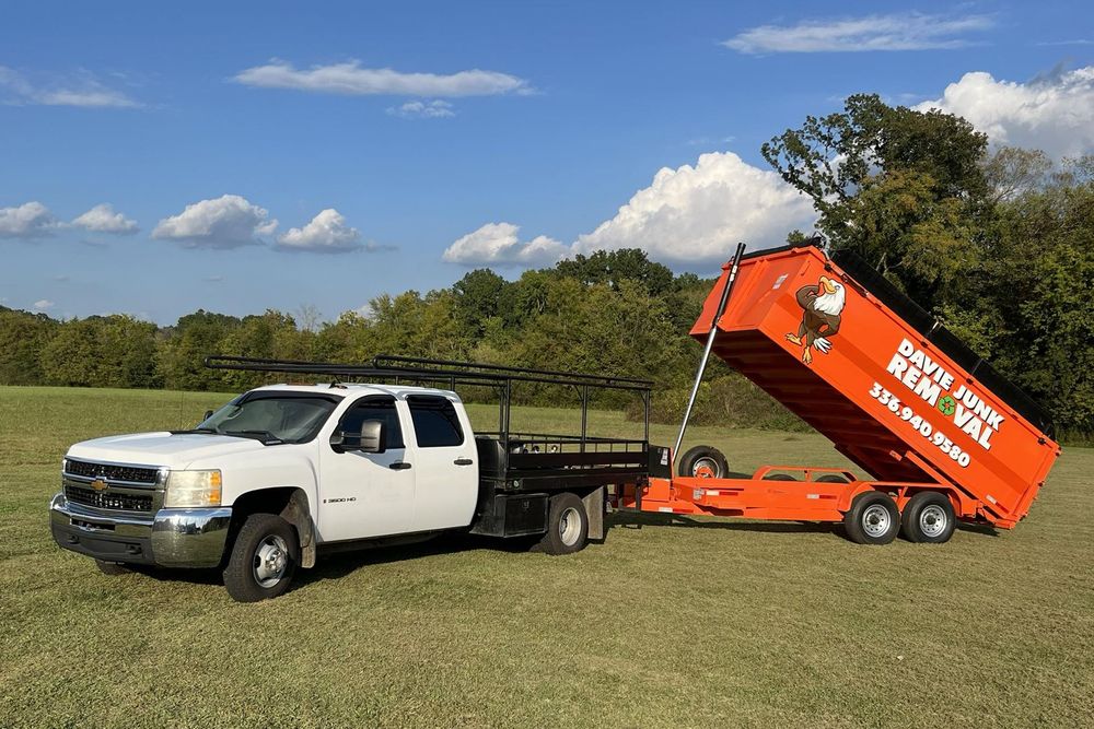 A white truck is pulling a red dumpster in a field.
