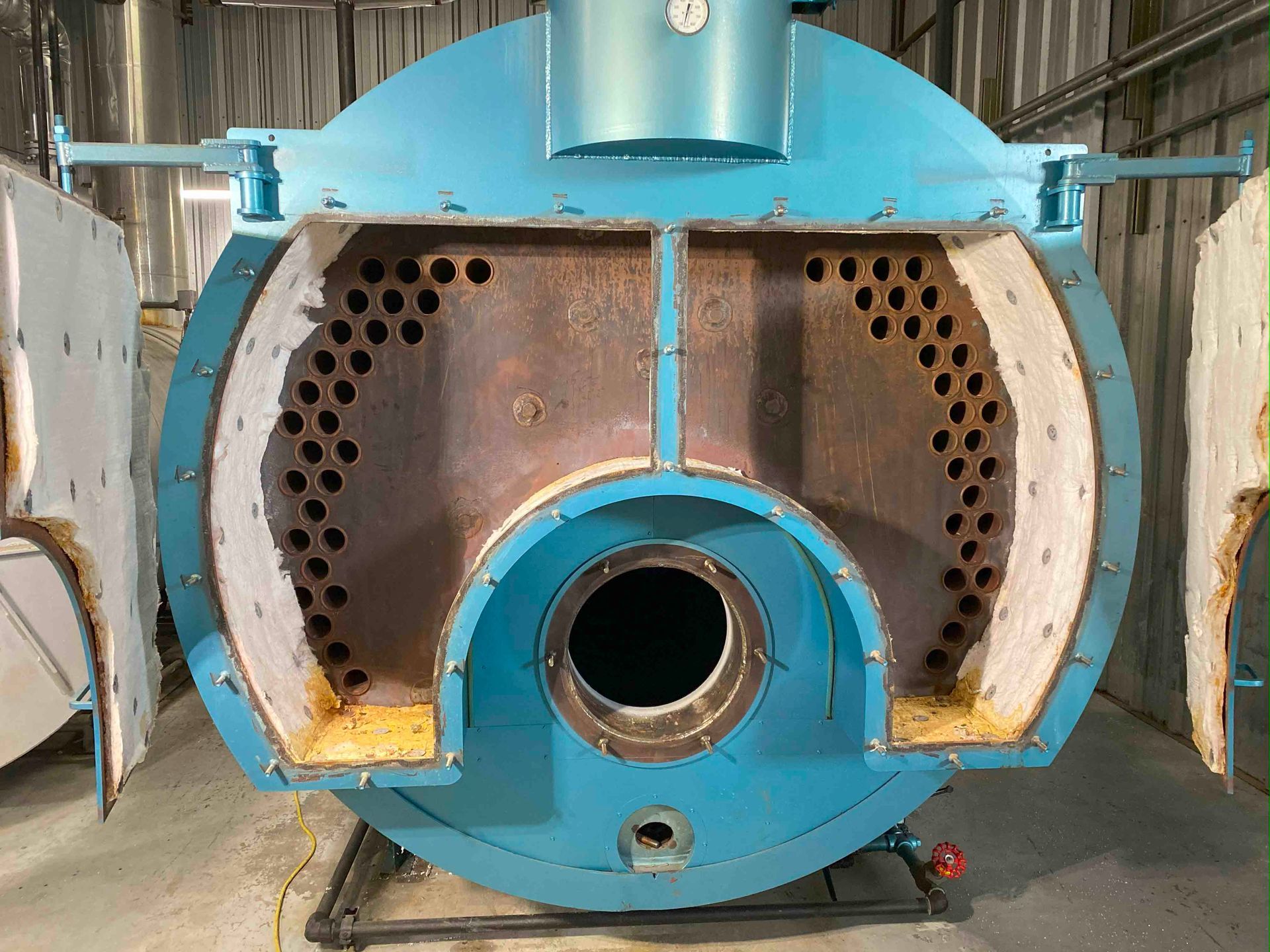 A large blue boiler is sitting in a warehouse.