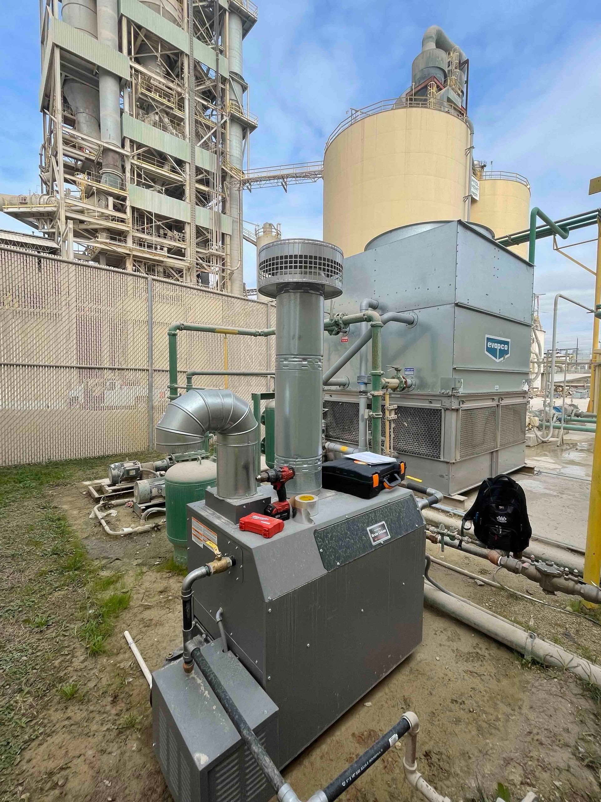 A machine is sitting in front of a large building in a factory.