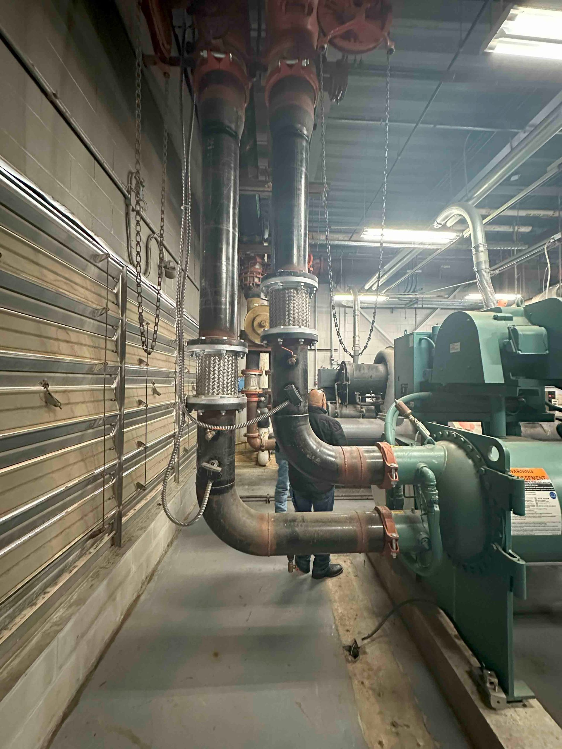 A man is standing in a room filled with pipes and machinery.