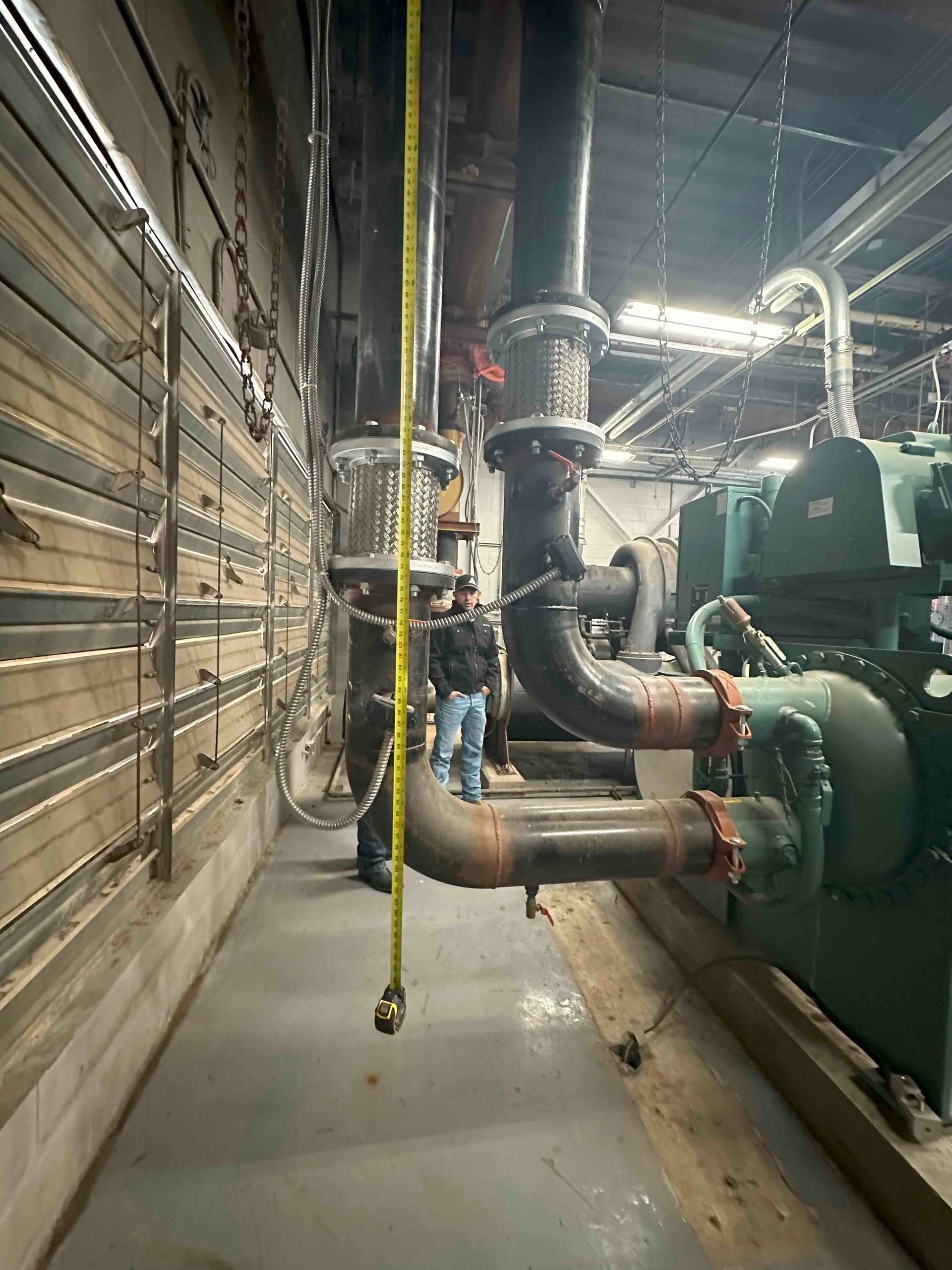 A man is measuring a pipe in a factory.