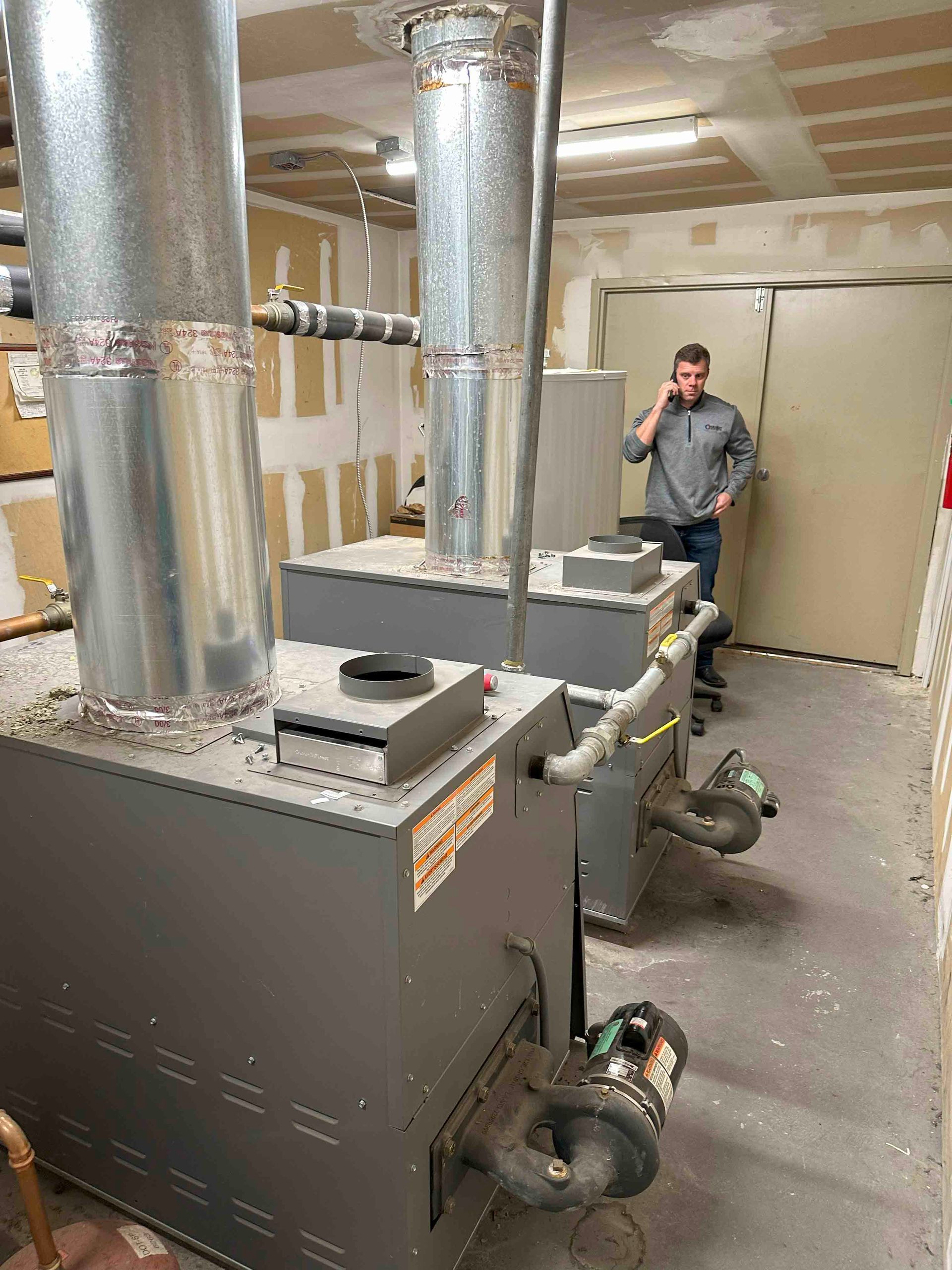 A man is standing in a room talking on a cell phone.