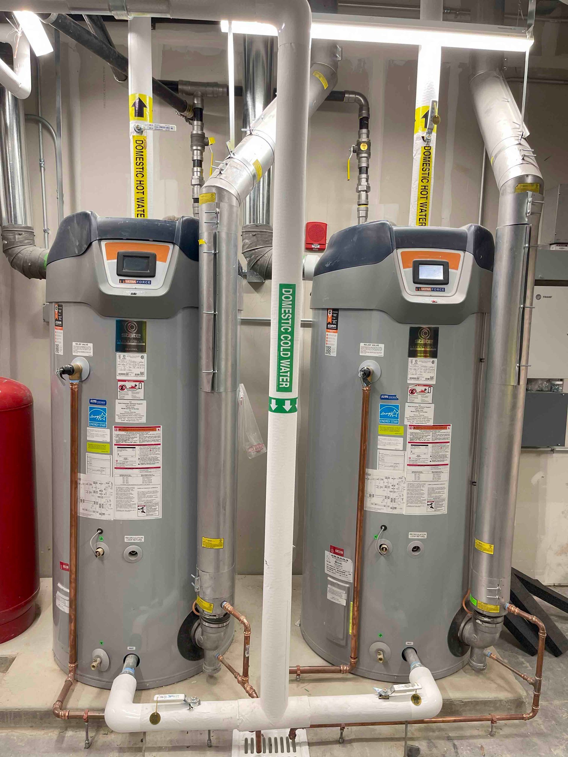 Two water heaters are sitting next to each other in a room.