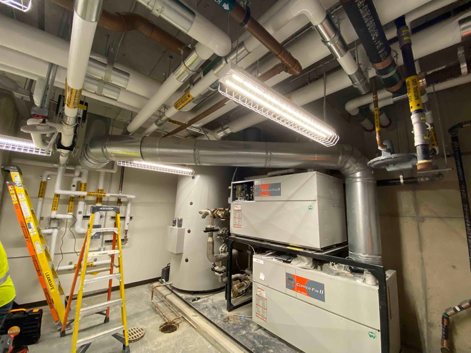 A room with a lot of pipes and a ladder in it