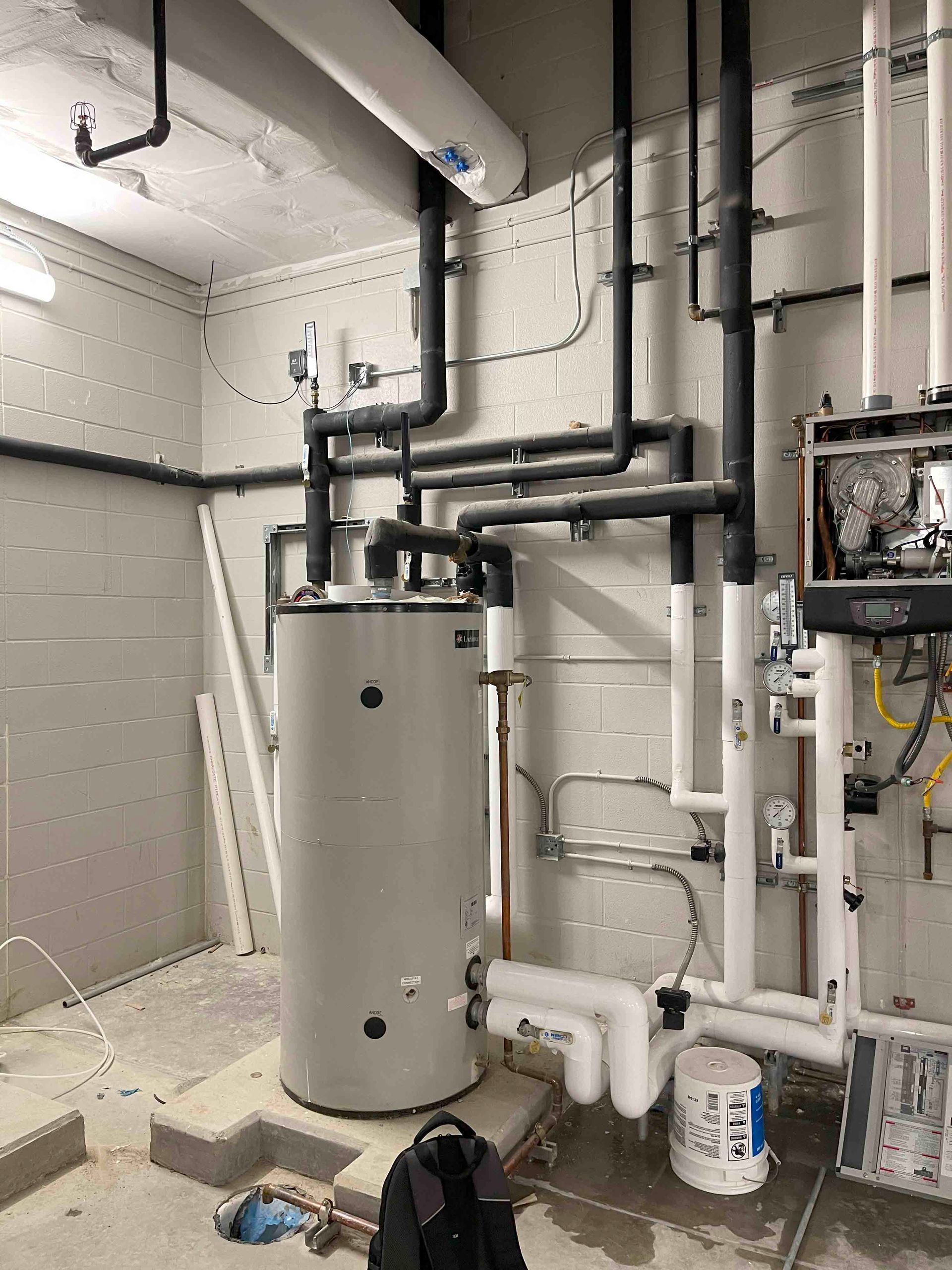 A room with a water heater and pipes in it.