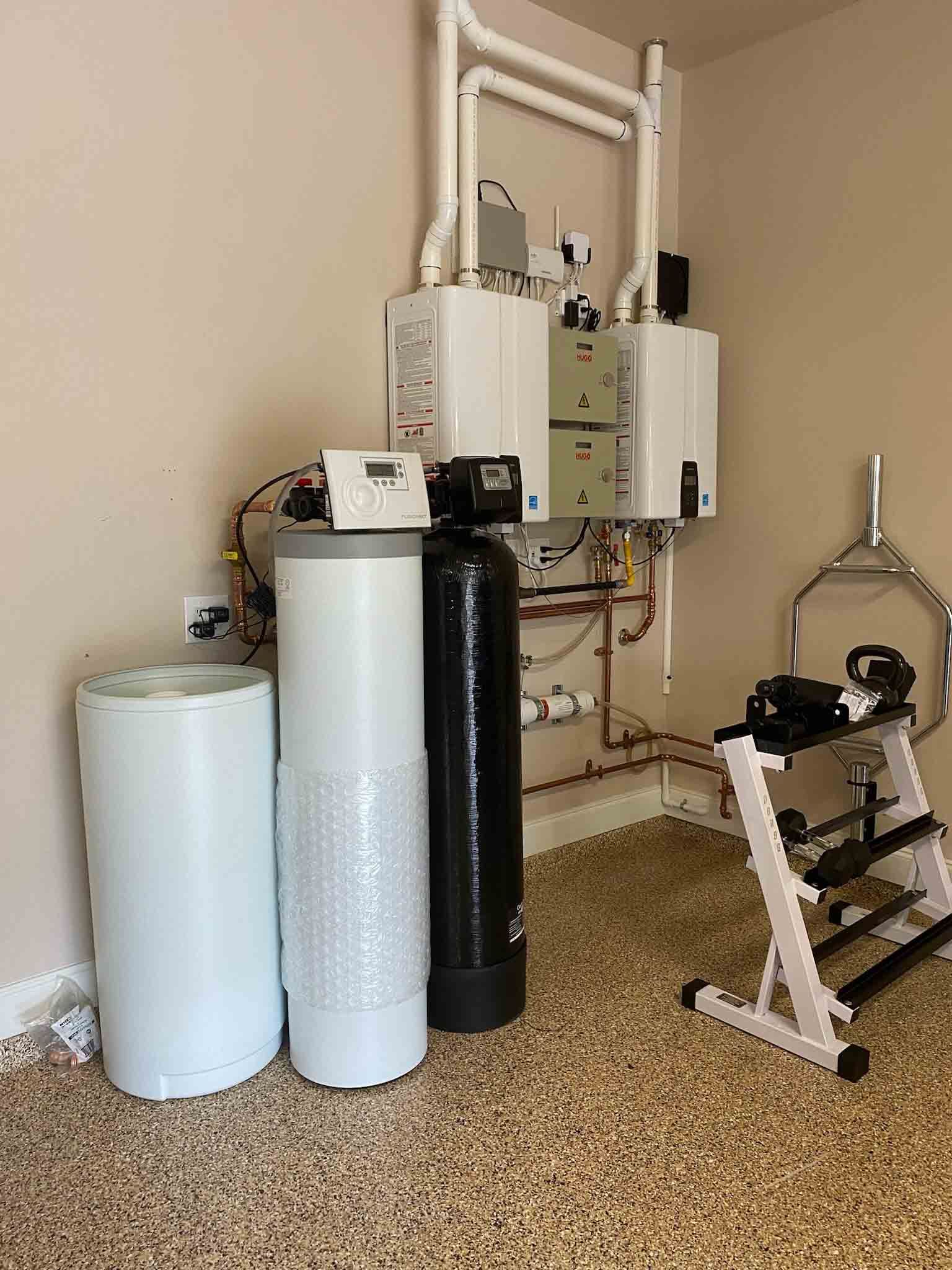 A room with a lot of pipes and a dumbbell rack.