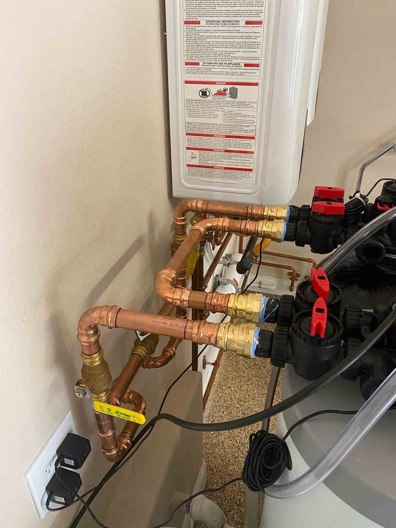 A room with a lot of pipes and a water heater.