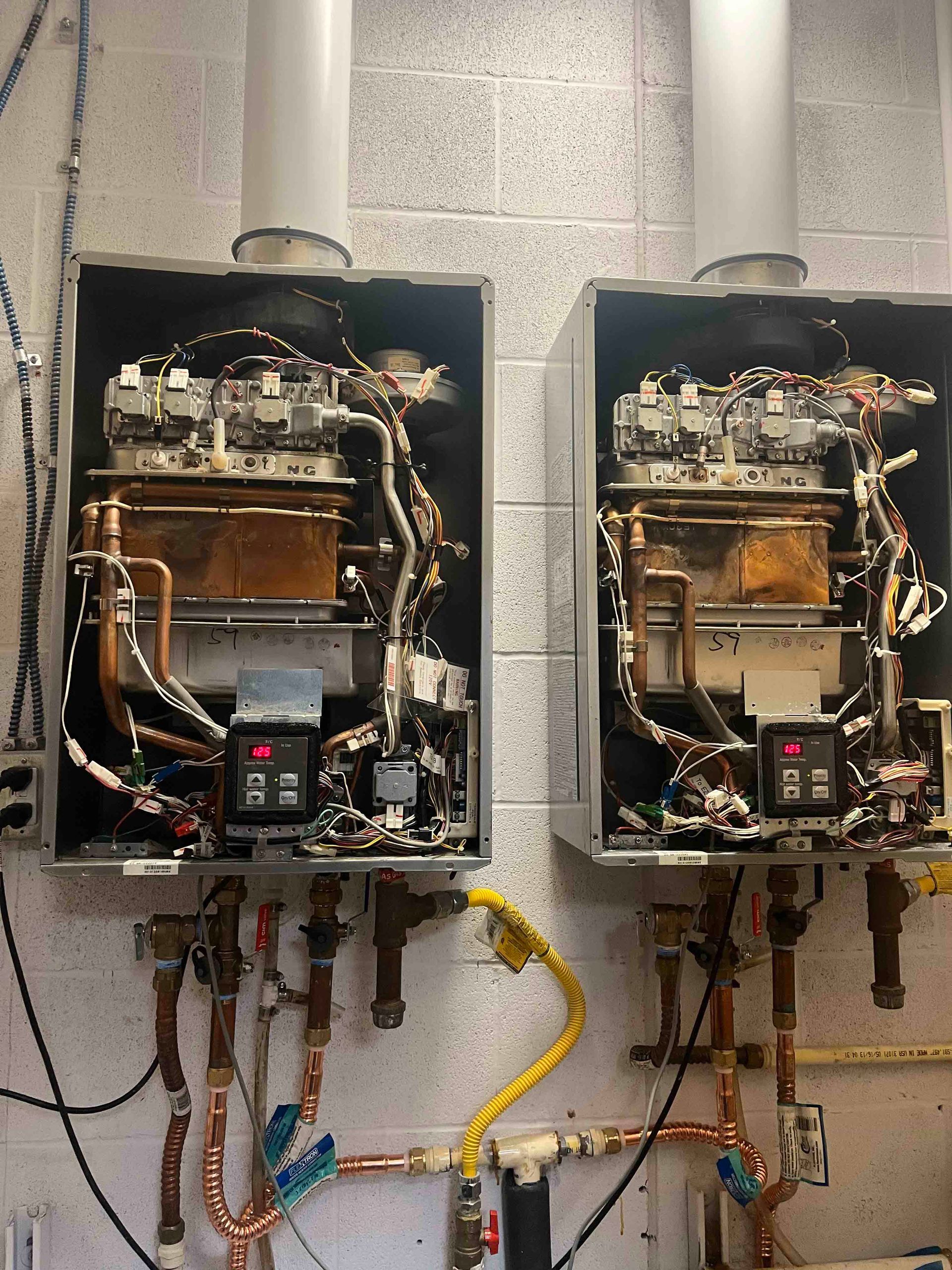 Two water heaters are sitting next to each other on a wall.