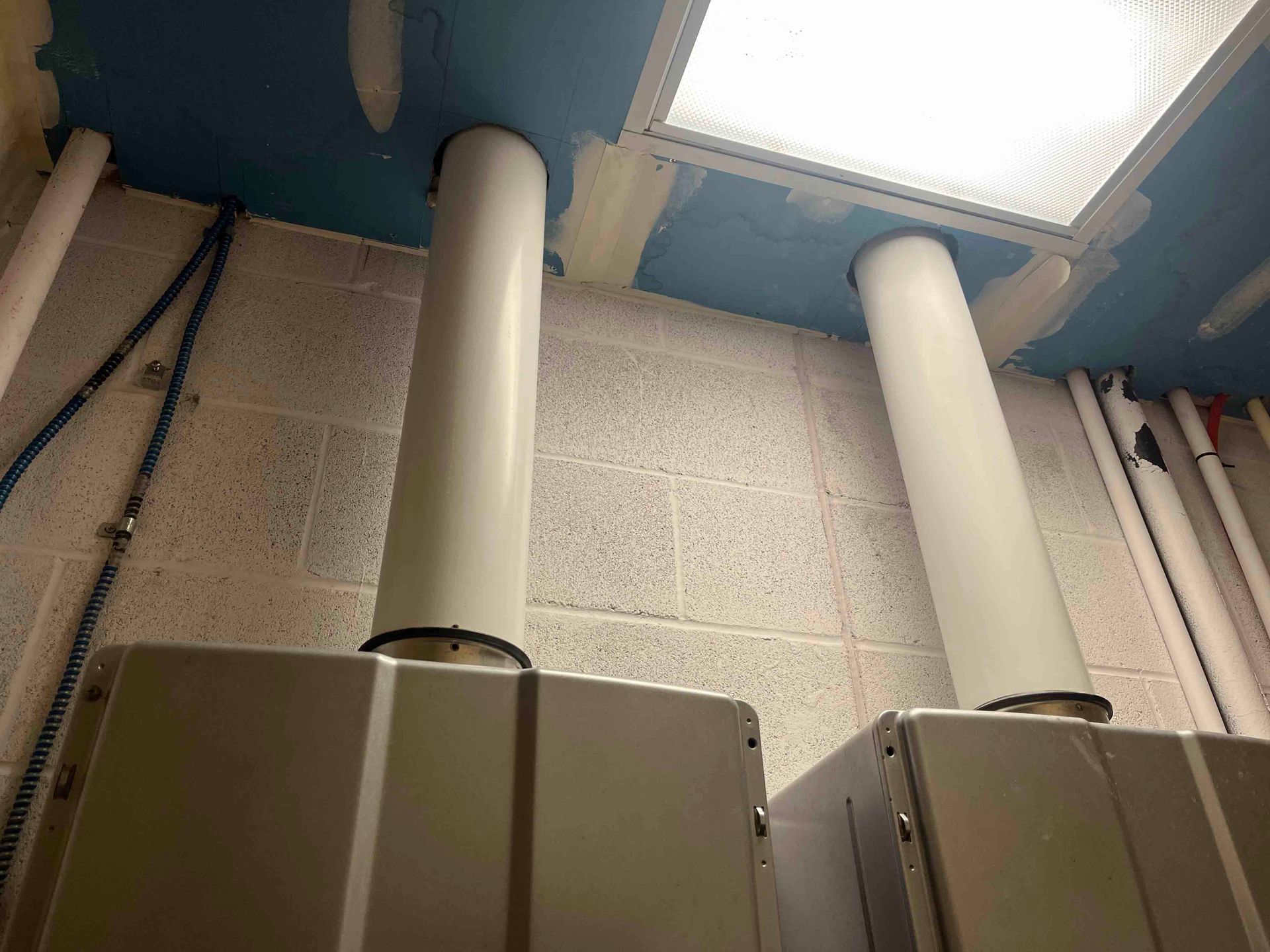 A room with a lot of pipes and a light on the ceiling.