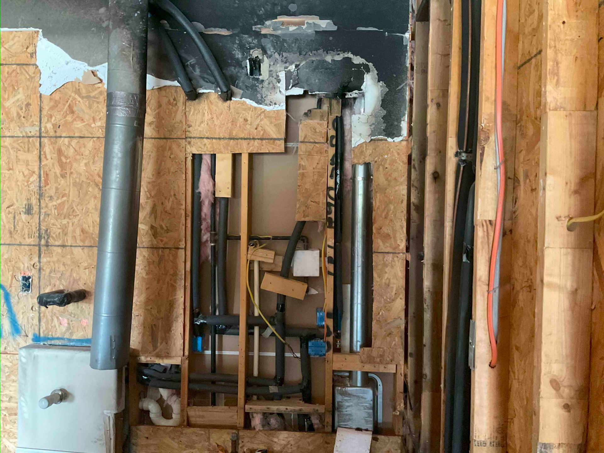 A wooden wall with pipes and wires coming out of it.